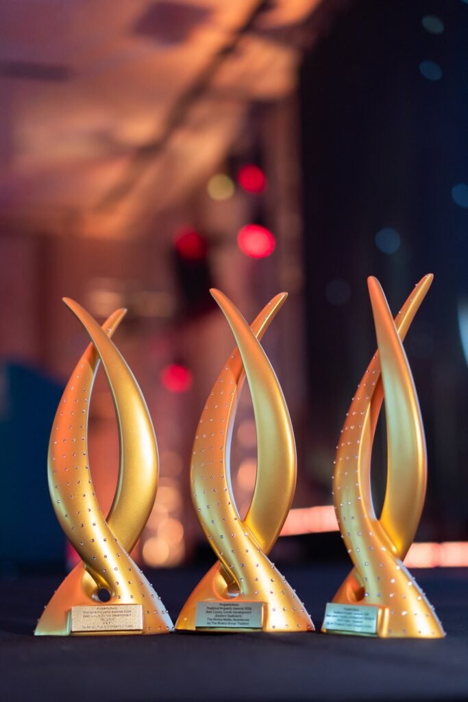 Three gold trophies on a dark stage under coloured lights at the 21st PropertyGuru Thailand Property Awards 2026