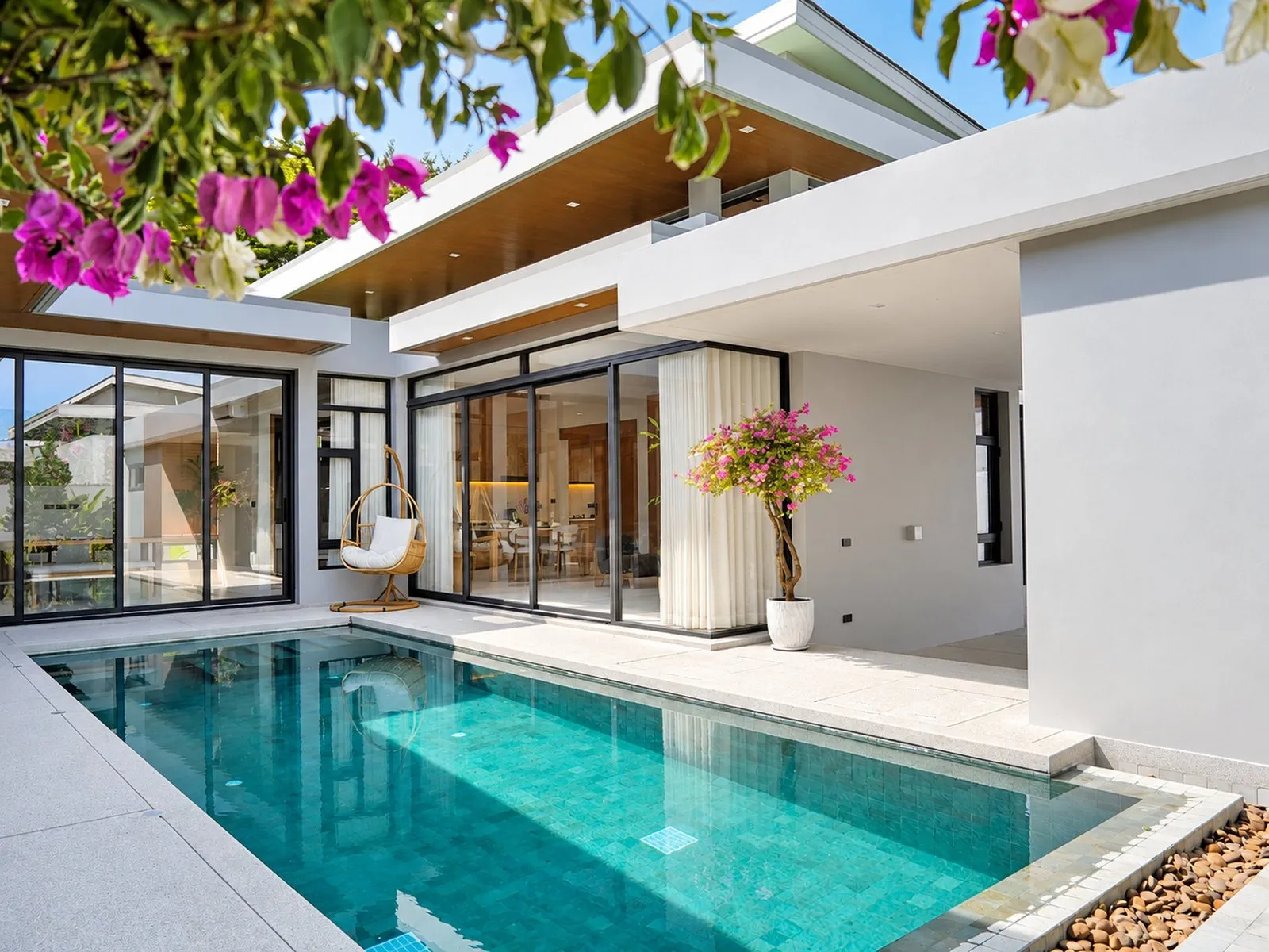 Pool courtyard with bougainvillea and glass-walled living areas at To’Summer Villa, Phuket